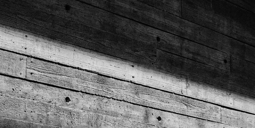 Board-formed concrete, raking light across the timber grain